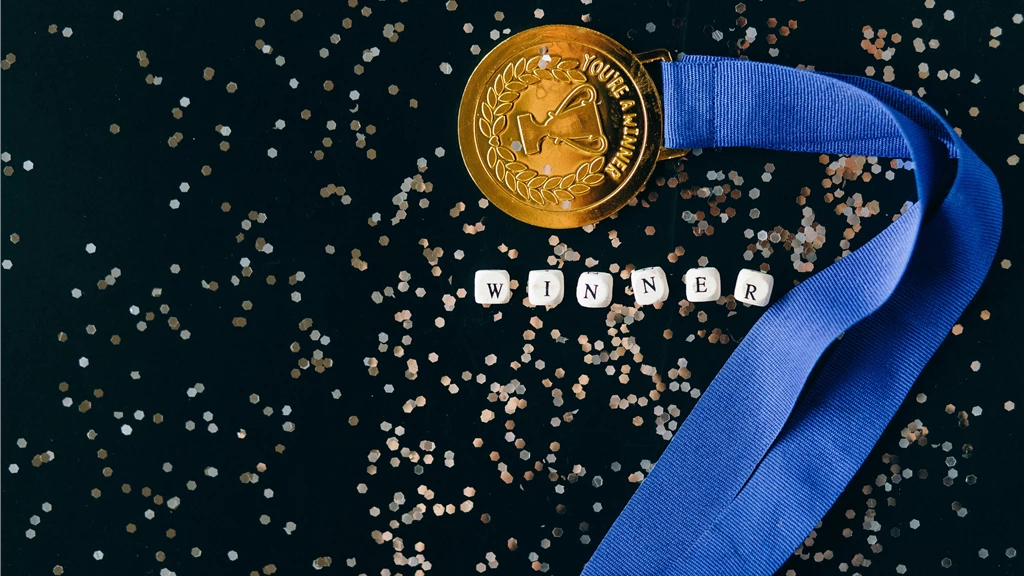 Close-Up Shot of a Gold Medal on a Black Surface
