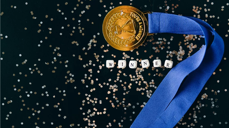Close-Up Shot of a Gold Medal on a Black Surface